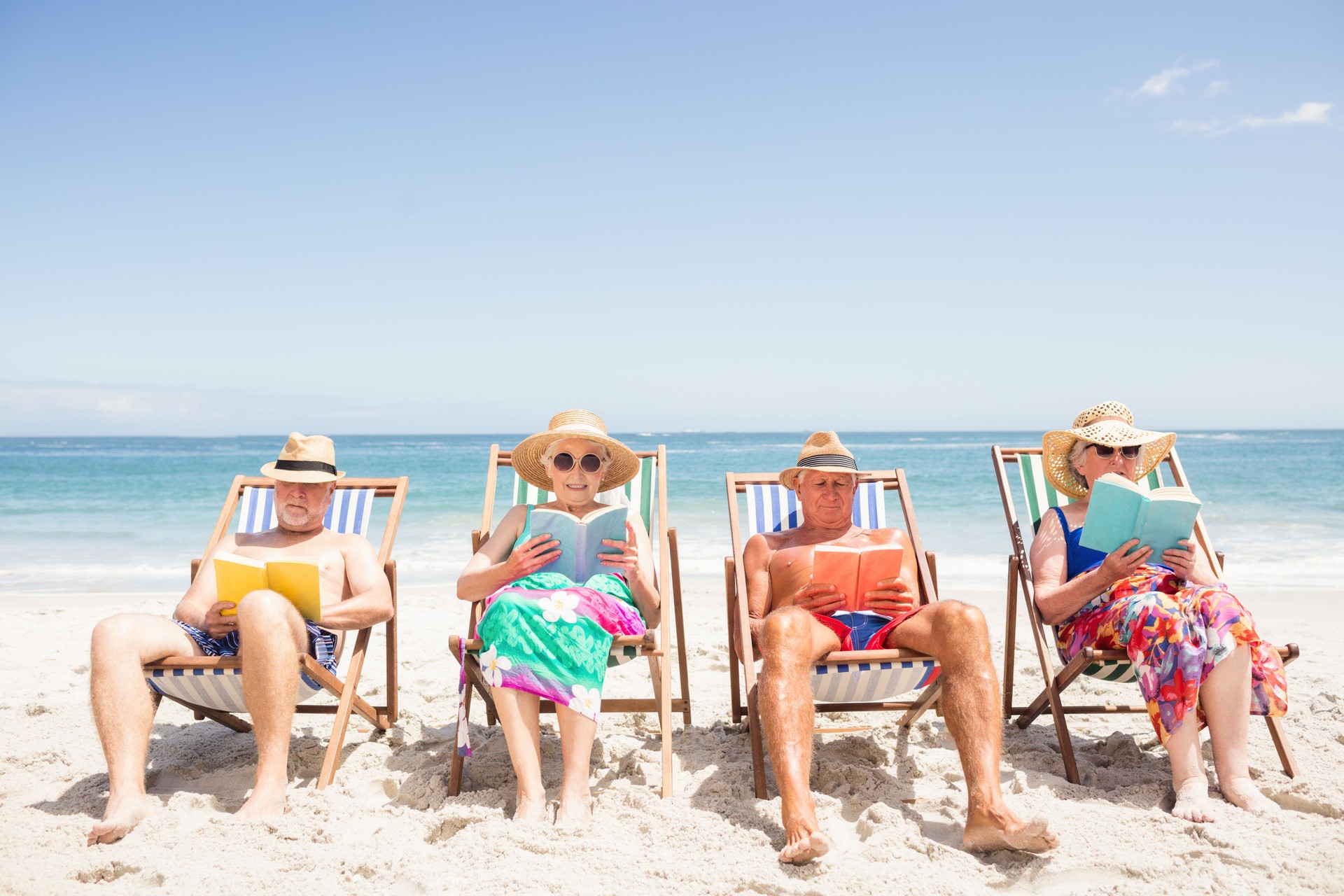 Senior friends reading books on beach chair