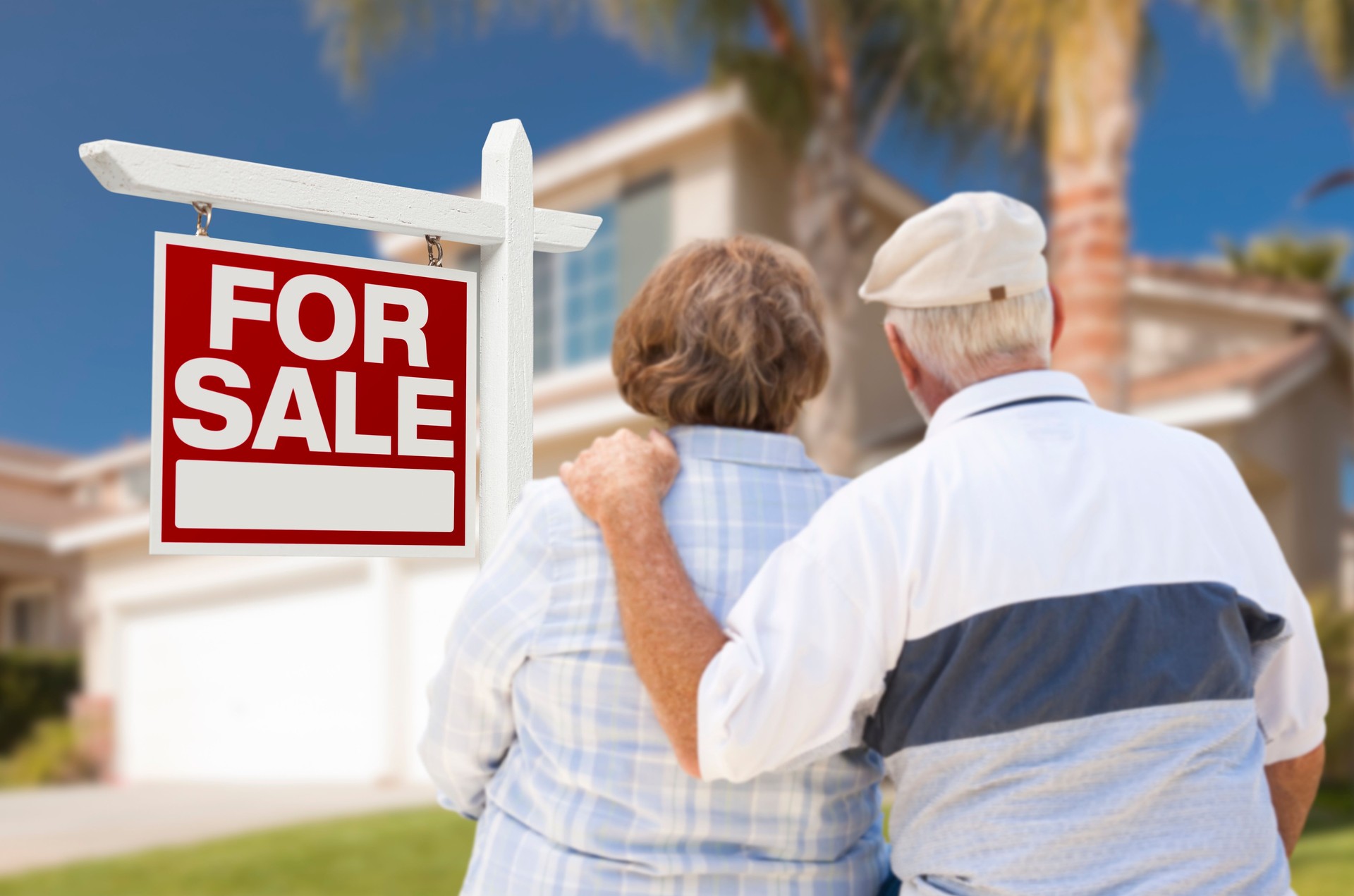 Happy Senior Couple Front of For Sale Sign and House